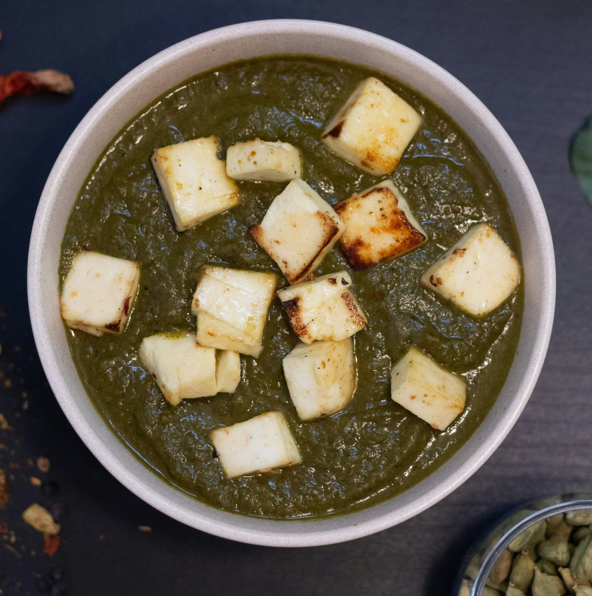 Spicey Saffron Palak Paneer – tender paneer cubes in a creamy spinach curry, served in a white bowl